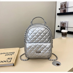 Nahaufnahme eines silbernen gesteppten Rucksacks mit Metallketten auf beigem Grund