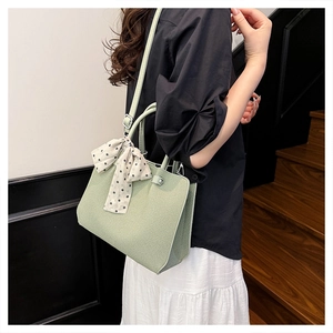 Vue détaillée du sac seau vert clair texturé avec ruban à pois sur la bandoulière