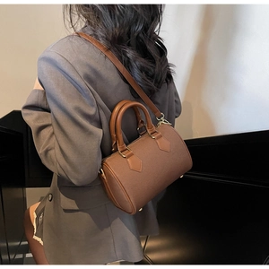 Detail of brown barrel bag in lychee texture leather with gold hardware on a model
