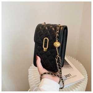 Detail of black quilted leather mini bag with gold chain strap and metal charm