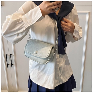Detail shot of light blue cross-body bag with litchi grain texture and silver metal hardware