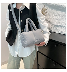 Gros plan détaillé sur la texture matelassée et la poignée rembourrée du sac cabas gris