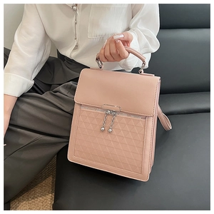 Detail of pink structured handbag with geometric embossing and metal ball pendants