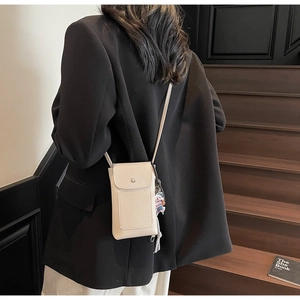 Détail d'un sac bandoulière en cuir grainé beige porté par un mannequin réel
