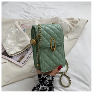 Detail of mint green quilted mini crossbody bag with gold globe charm and chain strap