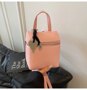Dettaglio borsa rosa in pelle martellata con ciondolo a cuore e chiusura a zip in metallo