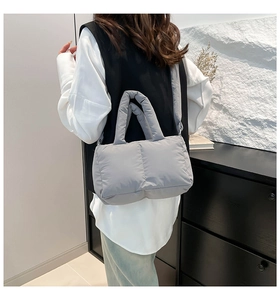 Vue détaillée d'un sac matelassé gris avec poignée épaisse et bandoulière amovible pratique