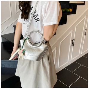 Detail of silver crocodile-embossed mini tote with round handle and pony charm detail