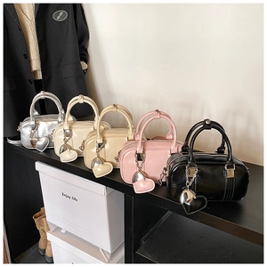 Detail of mini Boston bowling bags with heart charms in silver, beige, and pink colors