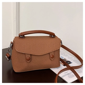 Detail of brown woven texture handbag with leather handle and silver metal hooks