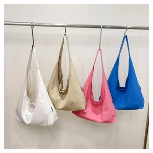 Row of minimalist canvas tote bags in white, khaki, pink, and blue hanging on metal hooks