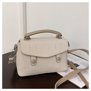 Detail of beige canvas crossbody bag featuring leather trim and silver metal hardware