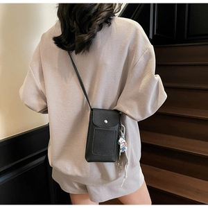 Détail du petit sac bandoulière en cuir grainé noir avec fermoir et breloque chien