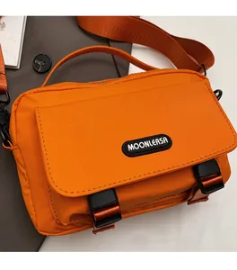 Detail of bright orange messenger bag featuring durable nylon fabric and plastic buckles