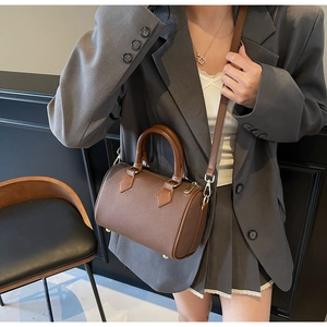 Detail of a dark brown Boston bag with leather trim on a model in a professional suit