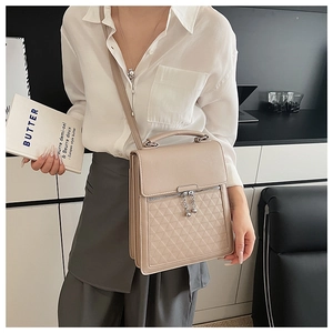 Detail of beige leather handbag with quilted pattern and decorative ball pendant