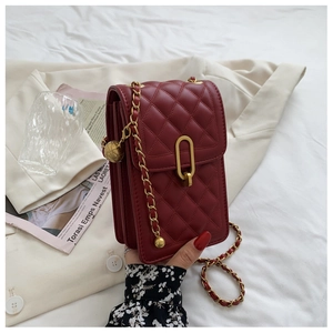 Detail of burgundy quilted leather handbag with gold chain strap and oval lock buckle