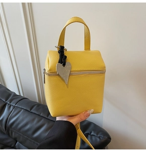 Dettaglio della borsa in pelle gialla martellata con pendente a cuore in argento