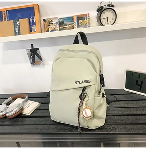 Dettaglio della borsa a tracolla verde chiaro con ciondolo baseball e logo STLANGS su panca