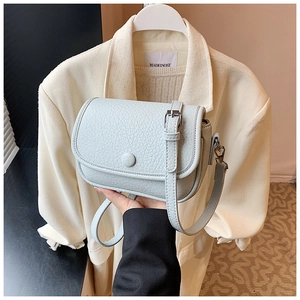 Detail showing mint green crossbody bag with lychee grain texture and silver buckles
