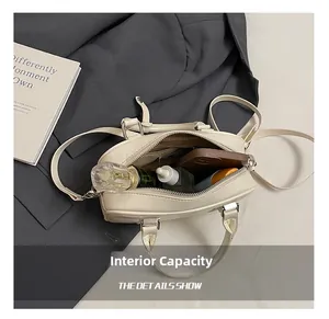 Spacious interior of a cream Boston bag showing capacity for perfume and phone
