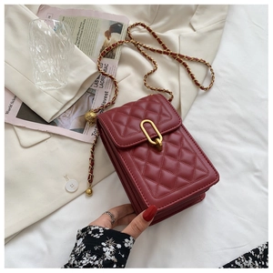 Macro shot of red quilted crossbody bag with gold chain and spherical metal buckle