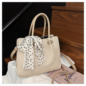 Détail du sac seau tissé beige avec écharpe en soie à pois et poignée en similicuir