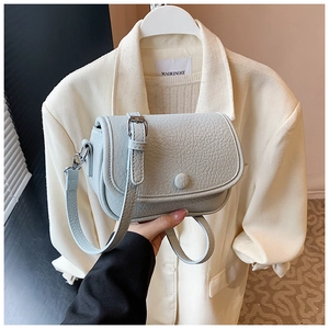 Detail of mint green small crossbody bag featuring lychee grain texture and round buckle