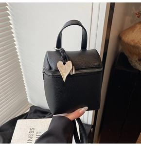 Dettaglio mini borsa in pelle nera con ciondolo a cuore in argento e manico superiore rigido