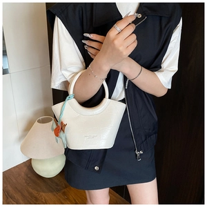 Detail of white crocodile pattern bucket bag with ring handle and horse charm