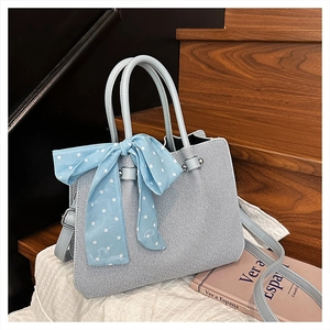 Détail du sac cabas bleu clair tressé avec nœud en ruban à pois et bandoulière