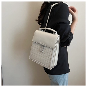 Detailed view of a white quilted handbag with silver zippers and elegant top handle