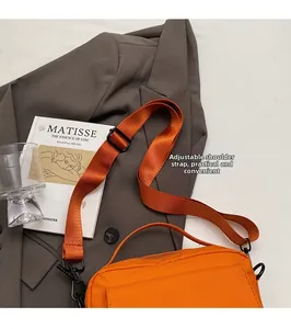 Detail view of the vibrant orange messenger bag with adjustable wide fabric shoulder strap