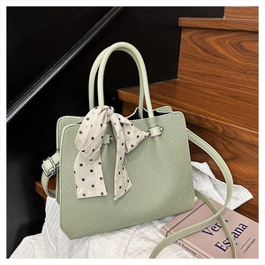 Détail du sac cabas tressé vert clair avec foulard à pois et bandoulière réglable
