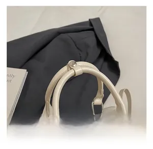 Close-up of cream bowling bag with dual cylindrical handles and silver metal hardware