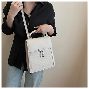 Detailed view of cream-colored faux leather bag featuring silver ball zipper pull and strap