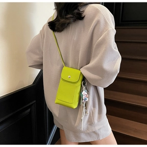 Vue détaillée du mini sac à bandoulière en cuir vert vif avec un petit pendentif ours