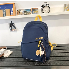 Dettaglio della borsa a tracolla in nylon blu navy con cerniere gialle e portachiavi da baseball
