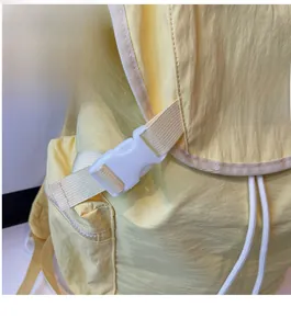 Close-up of durable white buckle and drawstring closure on a light yellow nylon backpack