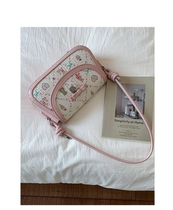 Detail of cute bow and heart charm on floral print crossbody bag with pink strap