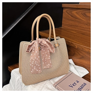 Détail du sac cabas en paille avec poignées en cuir et foulard décoratif en soie rose