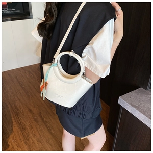 Close-up of white embossed leather basket bag with round handle and horse charm
