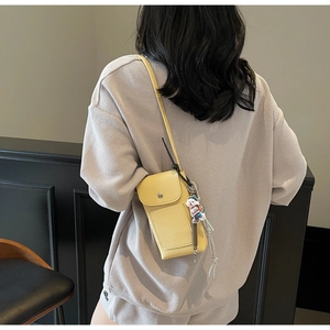 Détail d'un petit sac bandoulière jaune en cuir avec breloques mignonnes