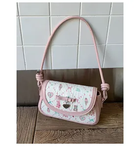 Detail of pink ballet-style crossbody bag with cute bow, heart charm and sweet prints