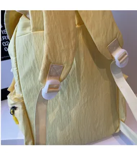 Close-up of lightweight yellow nylon backpack featuring wide padded straps and buckle detail