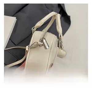 Close-up of silver metal hooks and zipper details on a cream leather bowling bag