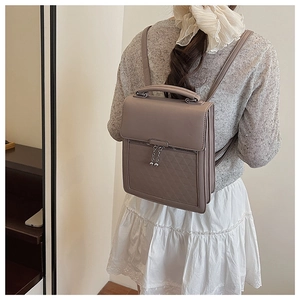 Detail showing grey faux leather backpack with quilted pattern and pearl zipper on model