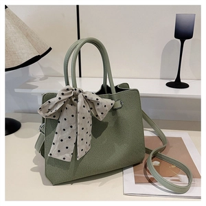 Gros plan du sac à main vert clair texturé orné d'un élégant foulard à pois noir et blanc