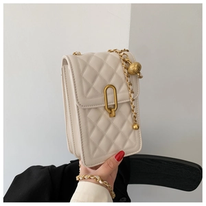 Detail of cream quilted crossbody bag with gold chain strap and spherical charm