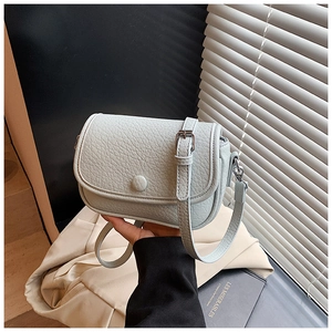 Detail of light blue crossbody bag featuring lychee texture and round decorative buckle